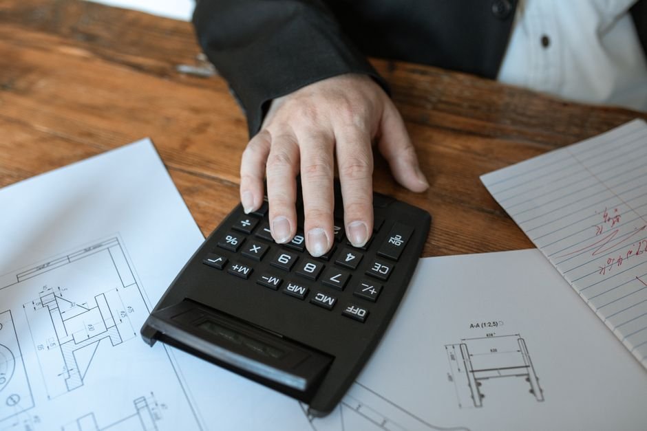 Main sur une calculatrice au-dessus de documents de budget