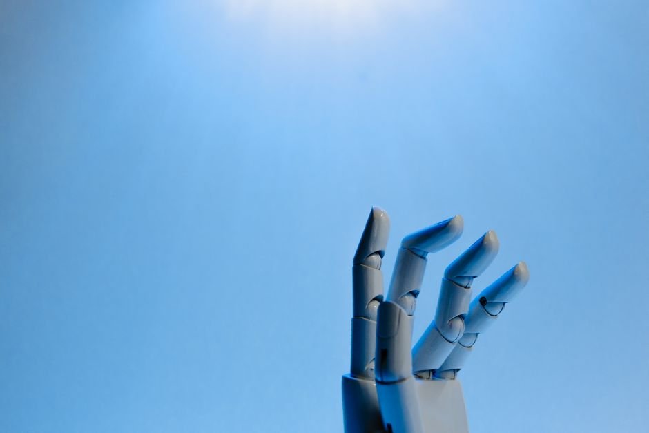 Main robotique se tendant vers le haut sur fond bleu